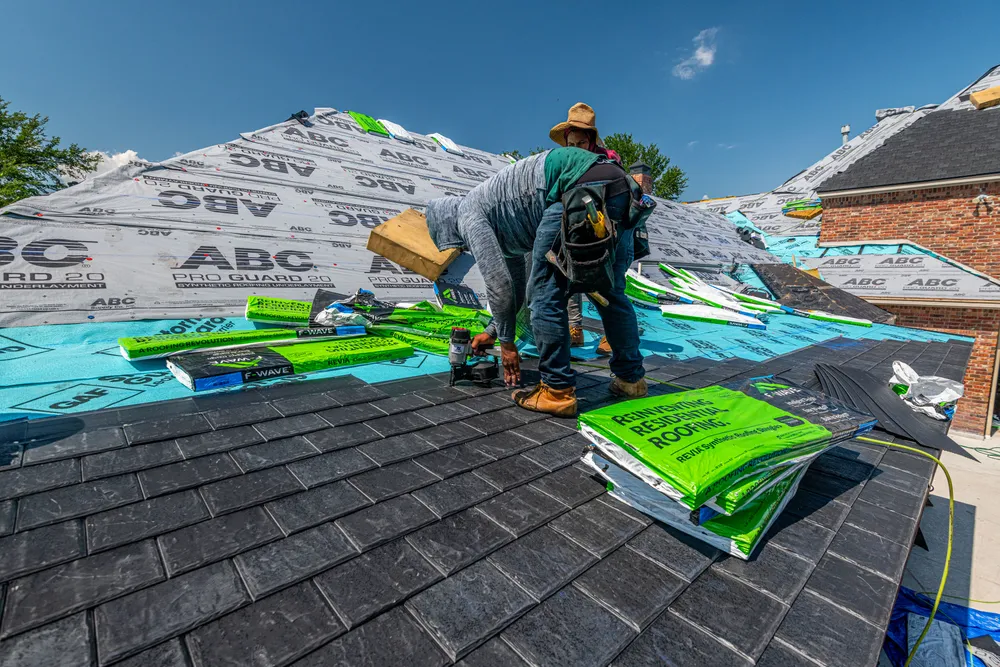 Roofing crew installing shingles on a home